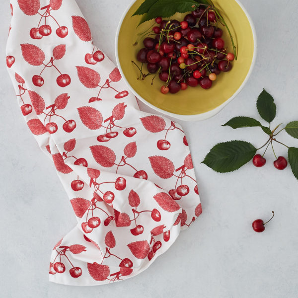 cherry cotton tea towel on a table with a bowl of cherries